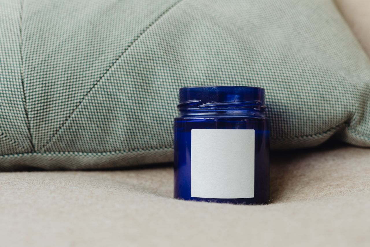 A blue container with a blank label, perfect for product mockups, against a cozy cushion backdrop.